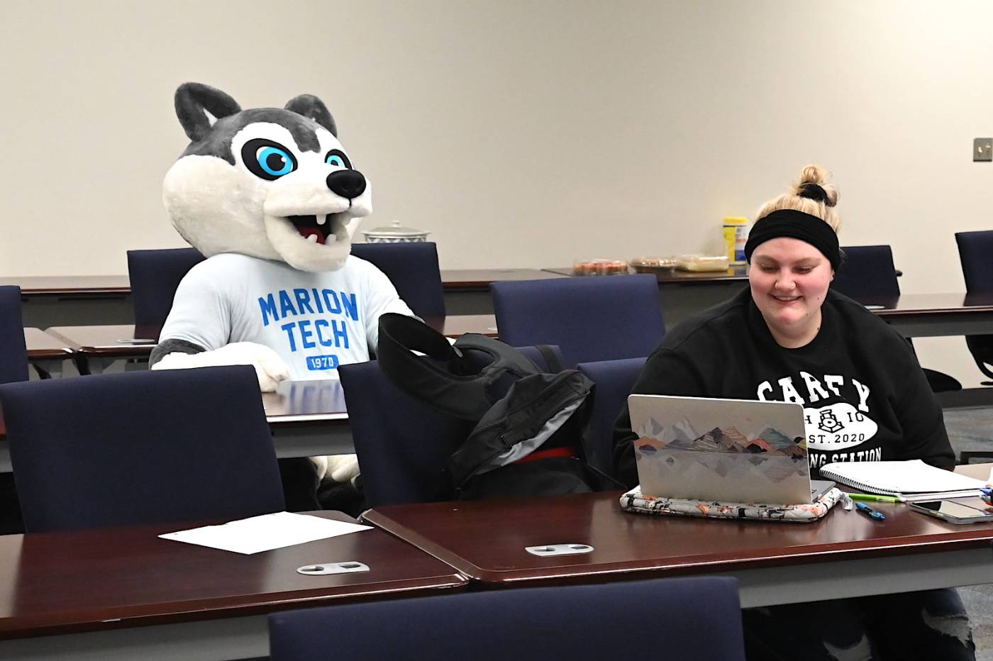 Female student and husky mascot sitting in classroom