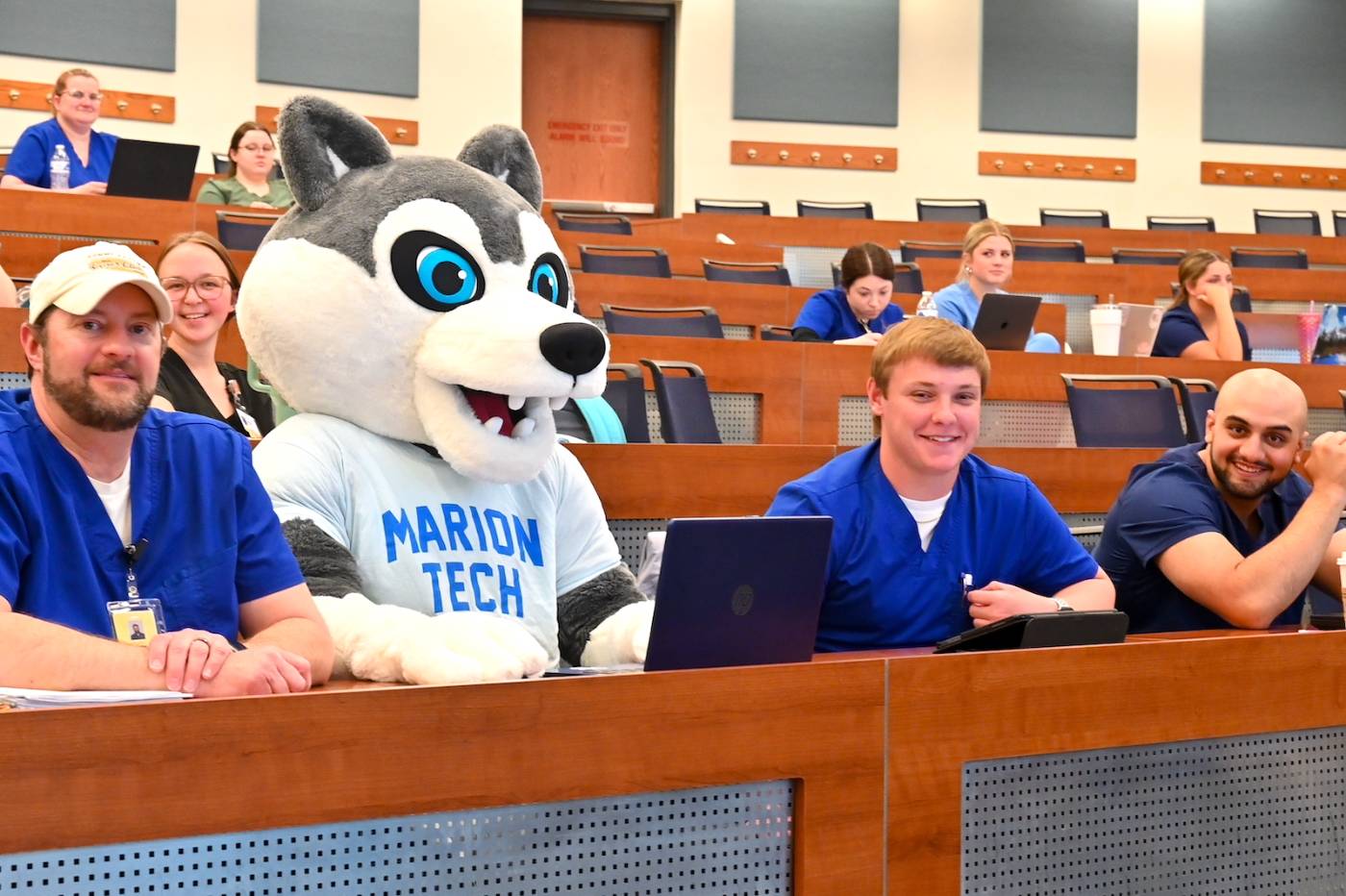 Male students with husky mascot in auditorium 