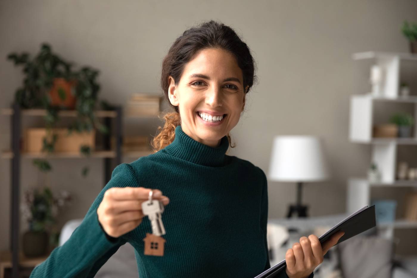 Female real estate agent holding paperwork and house keys